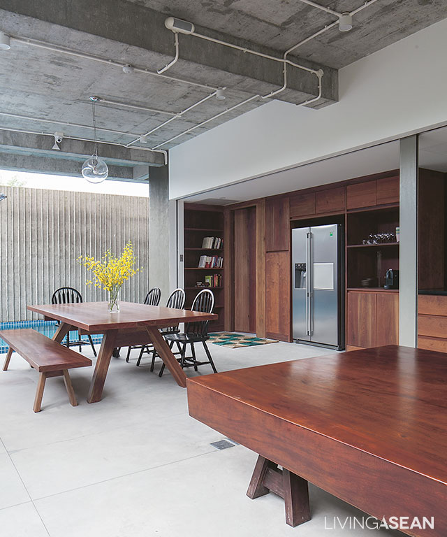 A large table with Windsor chairs and a vintage Chinoiserie daybed adorn the spacious, semi-outdoor dining room. Overhead, cement surfaces in the ceiling are brushed smooth for ease of maintenance and precautions against humidity damage.