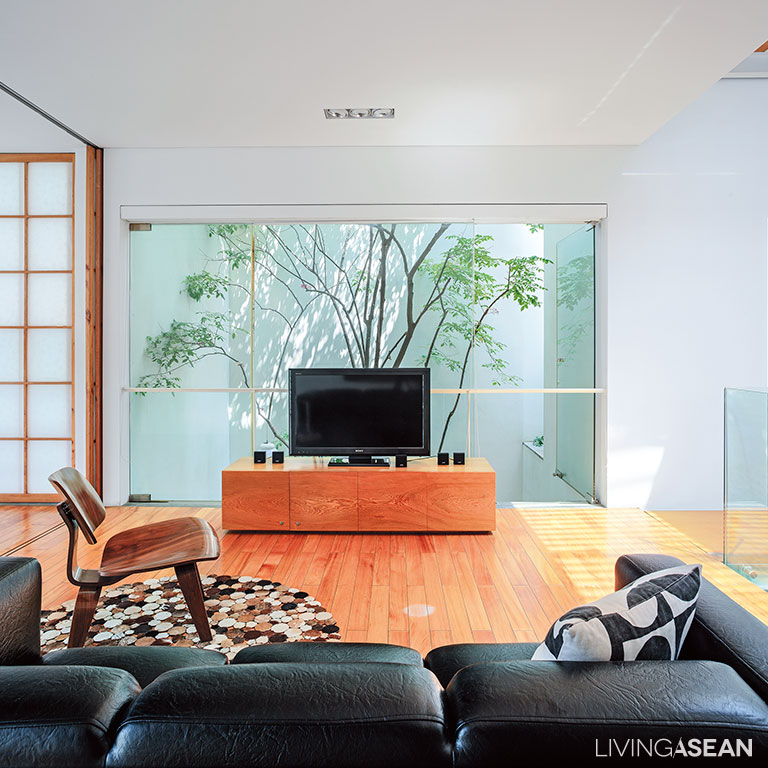 The second-floor living room is plain and uncluttered. A tree in the center courtyard blocks the sun’s rays from penetrating into the home.