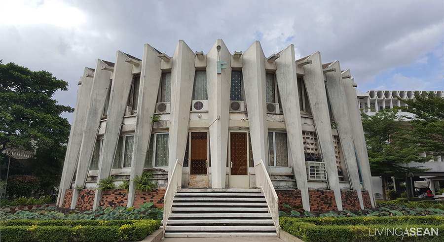 The Royal University of Phnom Penh's library building. Exterior pillars support the building weight (no pillars inside). The building is surrounded by a pond containing raindrops from a gutter. 