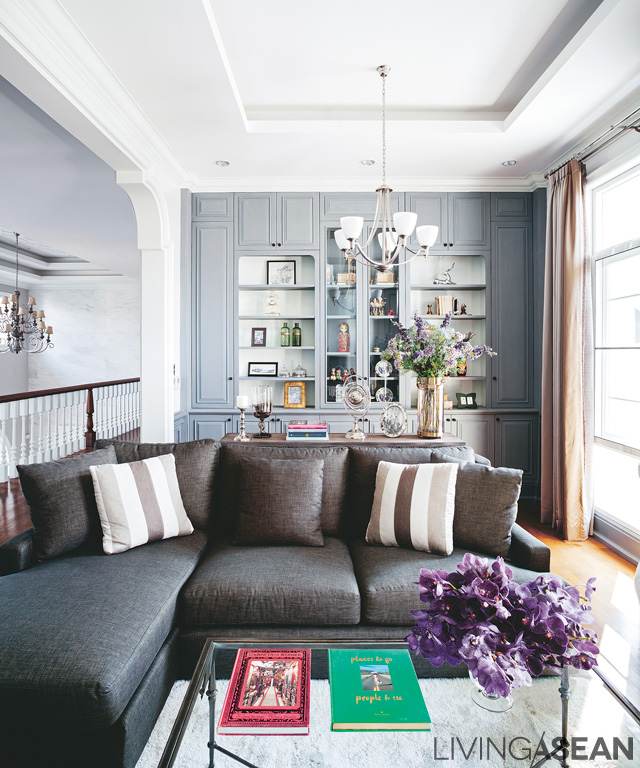 The “living room” corner on the second floor has grey shelves behind it. The strong brown of the sofa and gently patterned throw pillows give warmth to the room and make it an attractive place to be. 