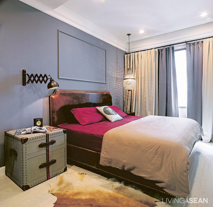 The bedroom is simple but striking. The pigeon-gray wall contrasts with the crimson bed sheet. Gimmicks lie in details, such as using an industrial lamp instead of an ordinary reading light, while a fancy crystal chandelier-like lamp is hanging on the far side. 