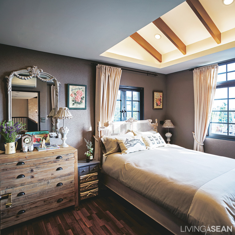 The master bedroom with charming country-style furnishings: Wooden beams are set above the bed for decorative effect. Recessed and indirect lighting provides a soft, relaxing illumination. 