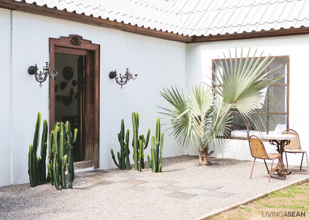 The unpaved center court surfaced with gravel provides easy access to all parts of the property. Houseplants, including cactus, thrive on the edge next to the exterior wall. 