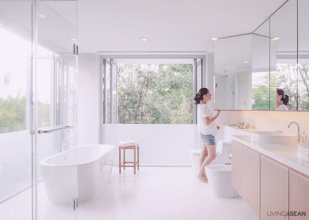 The bathroom is intentionally designed to be open and spacious, as a lot of light is wanted. There are frosted-glass guard railing and shower curtains that help make the space more private.