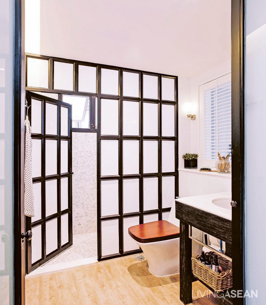 Oat replaced the old bathtub with a shower, separating dry and wet bathroom areas with a black-framed metal partition. The wood tile floor here brings a warmer feeling and a connection with other rooms.