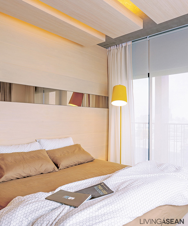  The shared bedroom is orderly and simple. Still, there is interesting detail: lighting works are hidden inside the lowered ceiling panels. The gaps in the ceiling are echoed with the long mirror set in the wood wall paneling. 