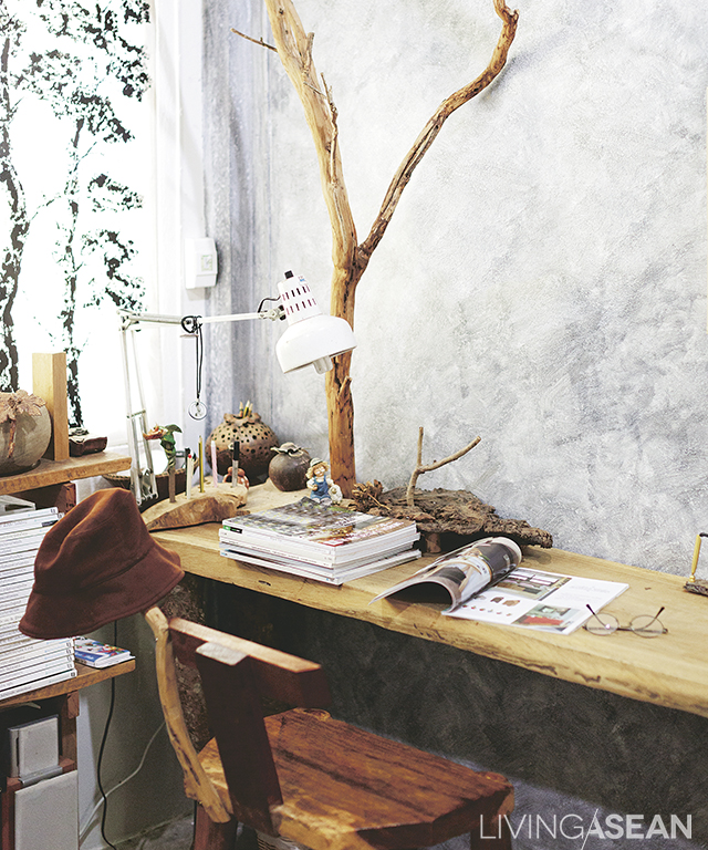 Twigs anchored against the rustic looking wall and furniture serve as racks for hanging hats and tchotchkes from a lifetime of carpentry. House and garden publications that are his pastime are kept here. 