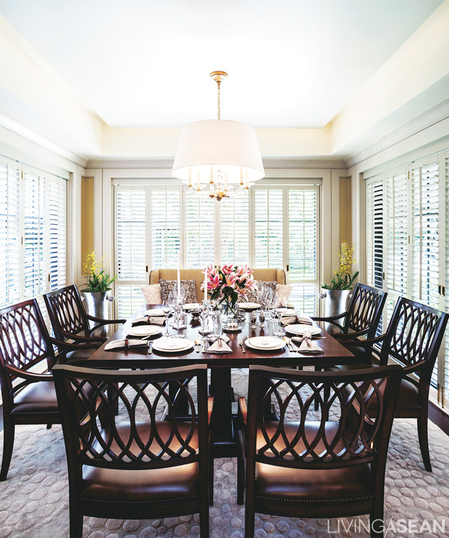 The dining room is ringed by glass to let in natural light during the day. The dark furniture color reinforces a warm, welcoming atmosphere.