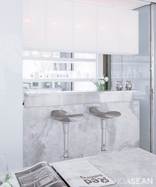 A mix of modern and oriental styles: The counter’s marble surface matches the dining table. Hanging lamps are tied to a white steel frame. 