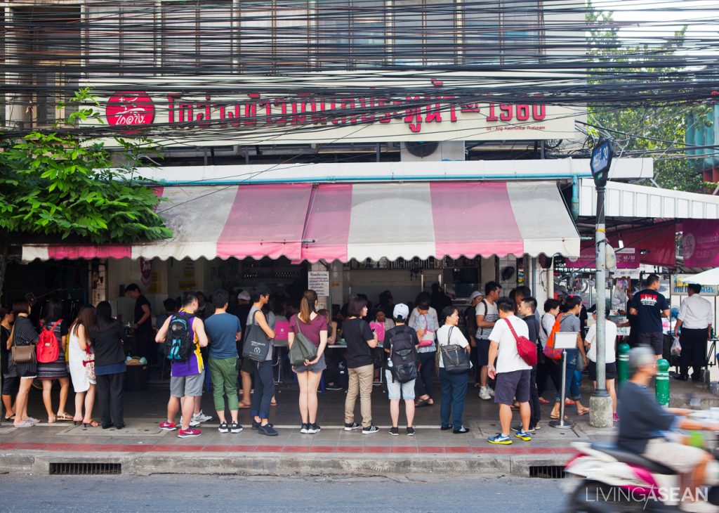 Customers queue up in front of a well-known chicken rice restaurant in Bangkok.