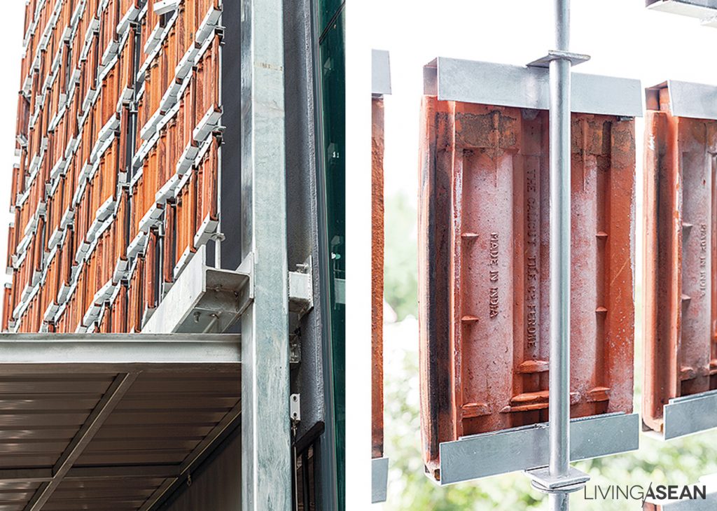 The decorative outer house wall uses a suspended steel framework to hold the terracotta roof tiles and red brick.