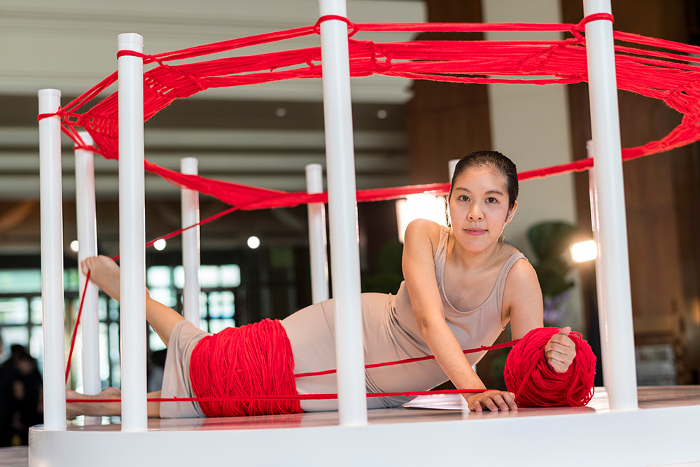 Like a shuttle on the loom, the artist puts her body in an imaginary knitting machine to portray real pain and suffering that women face in society.