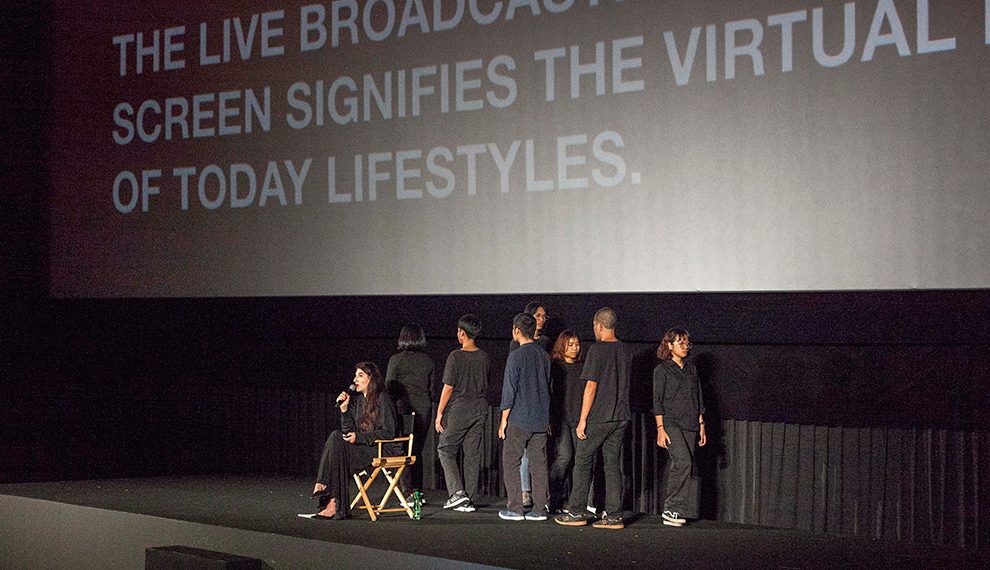 Abramovic speaks as young performers tread the stage slowly and quietly behind her.