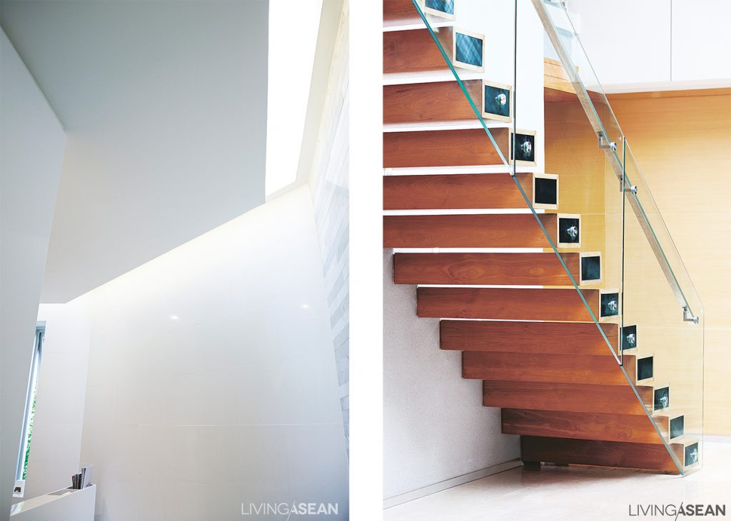 [Left] To make good use of daylight, a small skylight is cut in the upstairs bathroom. / [Right] The main staircase projects out from the wall. Light cream-colored genuine wood paneling and a clear glass railing make the stair look light, as if floating.