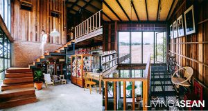 On one side of the hall is a staircase. Note the mix of unfinished wood, brick, cement, steel, and glass.