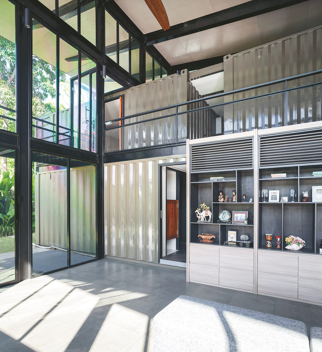 Another living room wall. On the ground floor is a washing area and bathroom. Clearly visible above is an arrangement of containers within the large steel frame.