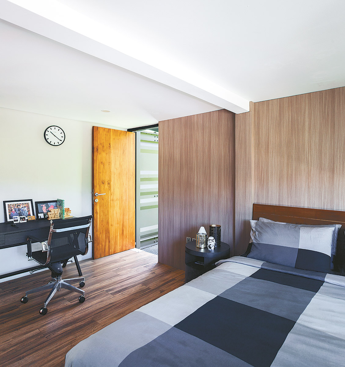 In the bedroom where the designer’s intent is to reduce the harshness of the steel with woodwork the walls and ceiling are white, as in an ordinary house. Utility systems are hidden in the pipe-like ceiling divider: the entire ceiling is not lowered, because of the height limitation of shipping containers.