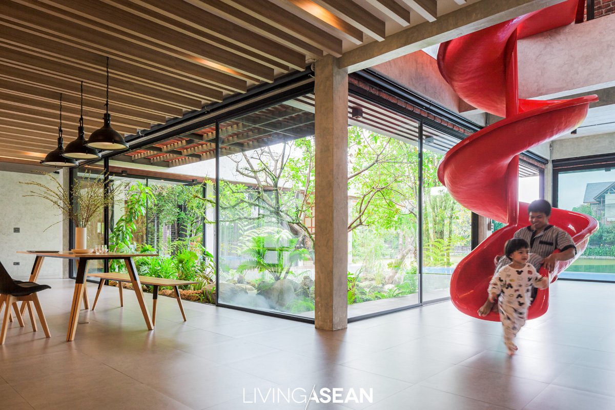 A red slide offers a fun way to enter to the living room, while the open floor plan gives the impression of more space and great reasons to float the furniture.