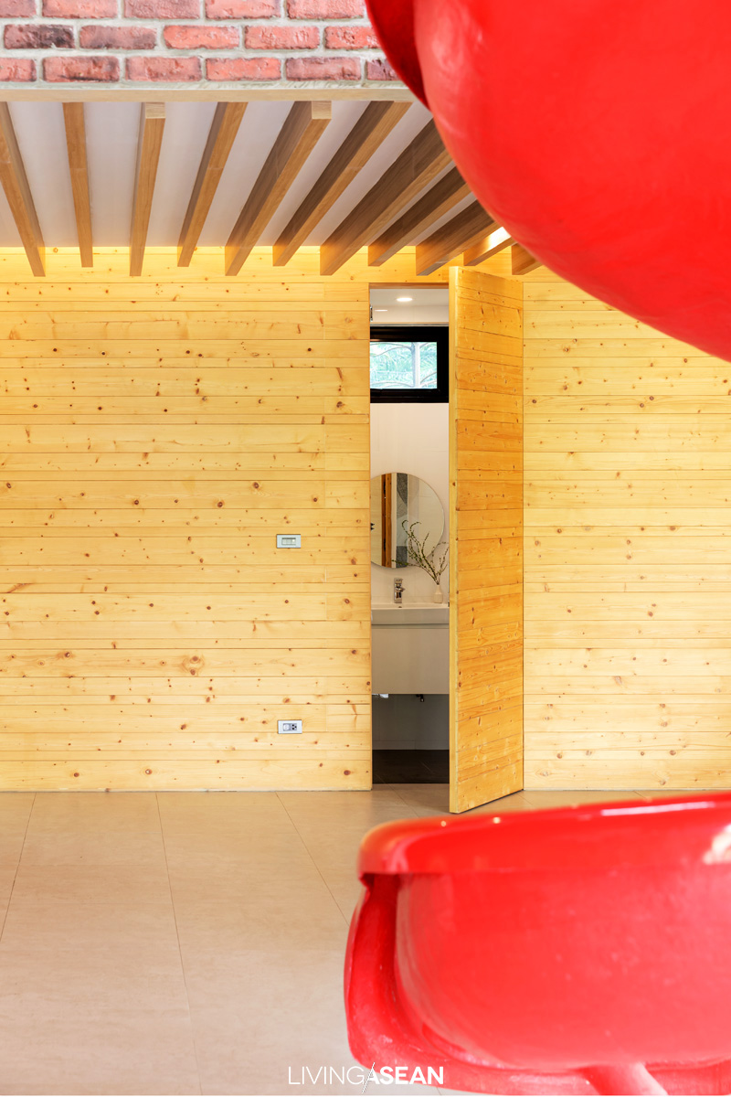 A bathroom is neatly concealed behind wood paneled walls in natural shades. Decorative wood paneling is inexpensive yet attractive. 